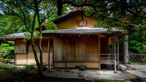 A traditional Japanese wooden house with a tiled roof nestled in a lush garden. jigsaw puzzle