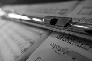 A silver flute rests on sheet music. jigsaw puzzle