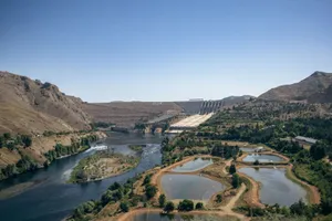 Beautiful landscape featuring a dam, river, and mountains under a clear summer sky. jigsaw puzzle