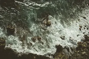 Dynamic aerial shot of ocean waves crashing onto a rocky shoreline, capturing the natural beauty and power of the sea. jigsaw puzzle