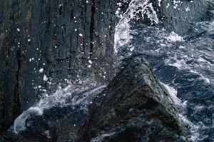 Close-up of ocean waves smashing against rugged rocks with water splashes creating dynamic textures. jigsaw puzzle