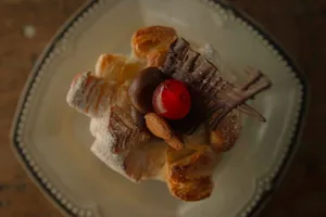 Close-up of a pastry topped with cherry, chocolate, and almonds on a plate. jigsaw puzzle
