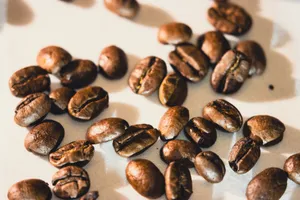 Bright close-up of roasted coffee beans scattered on white surface, ideal for coffee-themed designs. jigsaw puzzle