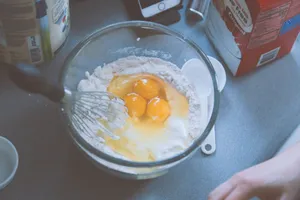 Close-up of mixing pancake batter with eggs and flour in a glass bowl. jigsaw puzzle