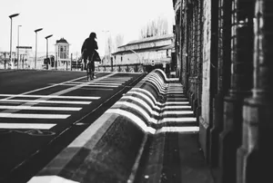 Black and white photo of a cyclist on a city street, emphasizing urban architecture and shadows. jigsaw puzzle