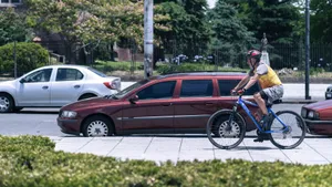 A man riding a bicycle on a city sidewalk on a sunny day. jigsaw puzzle