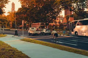Side view of anonymous man riding bicycle on asphalt road near vehicles during sunrise in city center jigsaw puzzle