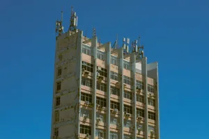 A tall urban building with antennas and a weathered exterior under a clear blue sky. jigsaw puzzle