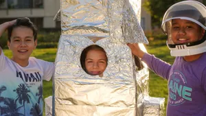 Three kids having fun with a cardboard rocket outdoors during the day. jigsaw puzzle