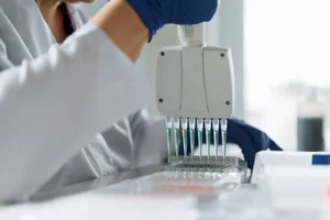 A scientist wearing a lab coat uses a multichannel pipette for liquid handling in a lab setting. jigsaw puzzle