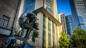 A metallic robot statue stands against modern skyscrapers under a clear sky. jigsaw puzzle