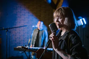 Smiling caucasian woman singing with vintage microphone during live music performance. jigsaw puzzle