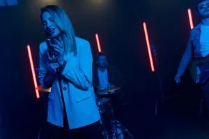 A vibrant band performance with singers and musicians under dramatic neon lighting on stage. jigsaw puzzle