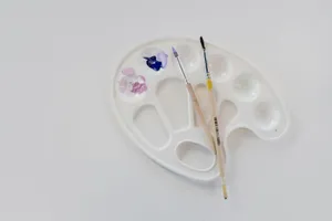 Flat lay of artist palette with brushes and paint on white surface, perfect for creative projects. jigsaw puzzle