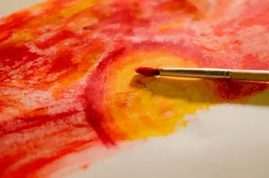 A dynamic abstract painting showcasing vibrant red and yellow hues with a paintbrush. jigsaw puzzle