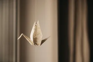 Minimalist close-up of a crafted origami crane suspended indoors. jigsaw puzzle