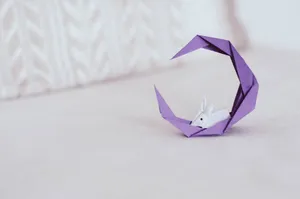 Elegant origami rabbit nestled in a purple paper crescent on a soft background. jigsaw puzzle