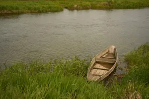 Wooden boat rests on grassy riverbank jigsaw puzzle