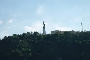 Monumental statue on a forested hill beneath a cloudy sky. jigsaw puzzle