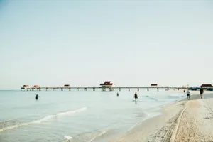 people are walking on the beach near a pier jigsaw puzzle