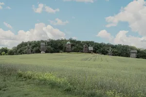 Wooden windmills on a green hill under a cloudy sky. jigsaw puzzle