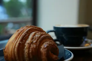 A croissant and a cup of coffee on a table jigsaw puzzle