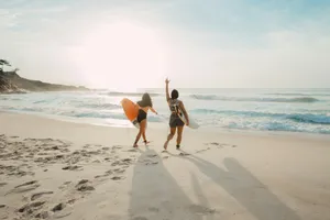 two women walking towards the ocean carrying surfboards during day jigsaw puzzle