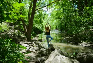 woman in blue tank top and blue leggings standing on gray rock near river during daytime jigsaw puzzle