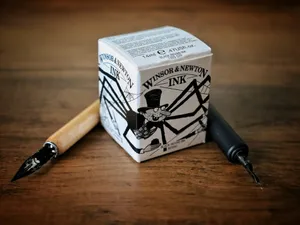 A pen sitting on top of a wooden table next to a box jigsaw puzzle