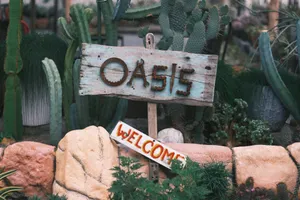 Charming rustic signboard reading 'Oasis Welcome' amidst lush cacti and stones. jigsaw puzzle
