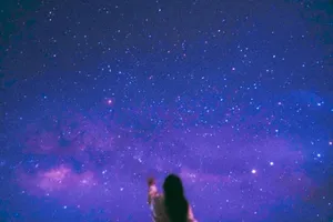 A silhouette of a person reaching towards a vivid starry night sky, featuring the Milky Way. jigsaw puzzle