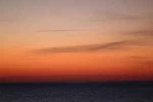 A breathtaking sunset view over a calm ocean horizon, showcasing vibrant orange hues and wispy clouds. jigsaw puzzle