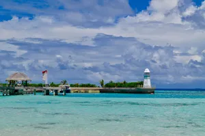 Scenic view of a tropical pier with a lighthouse and azure water under a vibrant sky. jigsaw puzzle